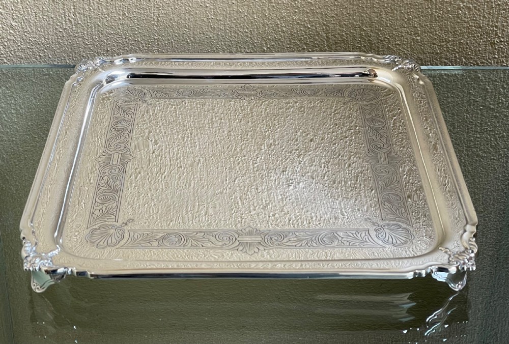 A square solid silver tray featuring hand-engraved scrollwork borders, shell corner accents, and a polished metallic surface. View II