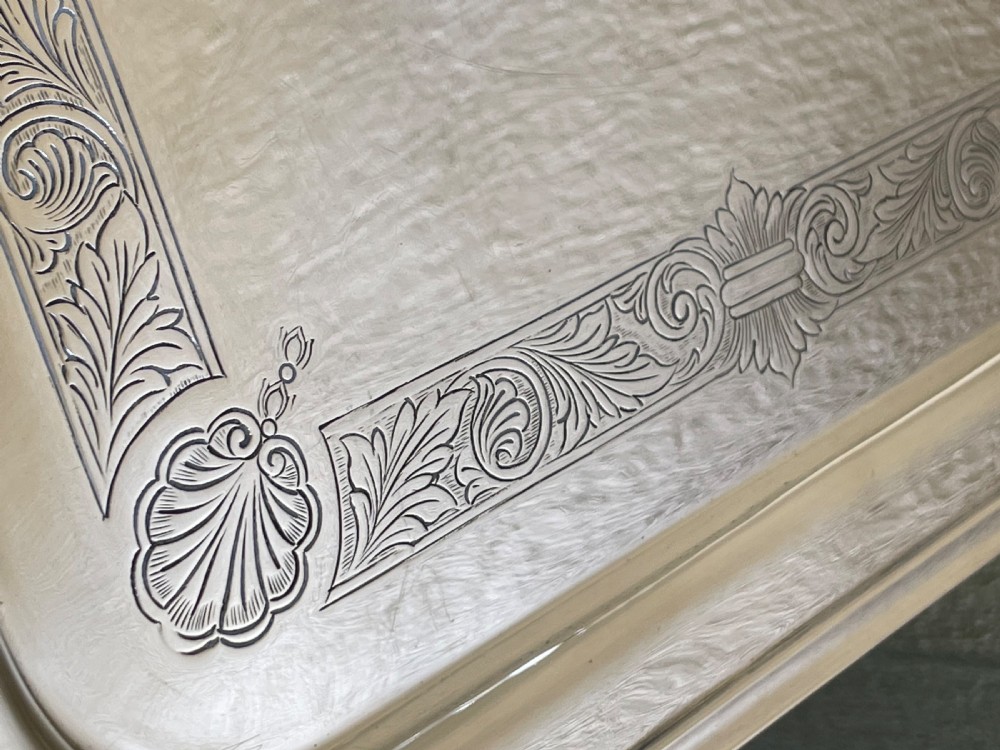 A square solid silver tray featuring hand-engraved scrollwork borders, shell corner accents, and a polished metallic surface. View III