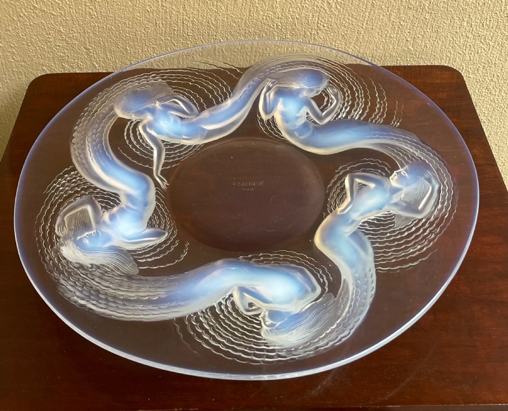 An Art Deco opalescent glass charger featuring moulded high-relief depictions of five swirling sirens around a central recessed reservoir.