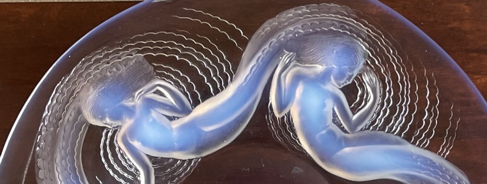 An Art Deco opalescent glass charger featuring moulded high-relief depictions of five swirling sirens around a central recessed reservoir. View IV