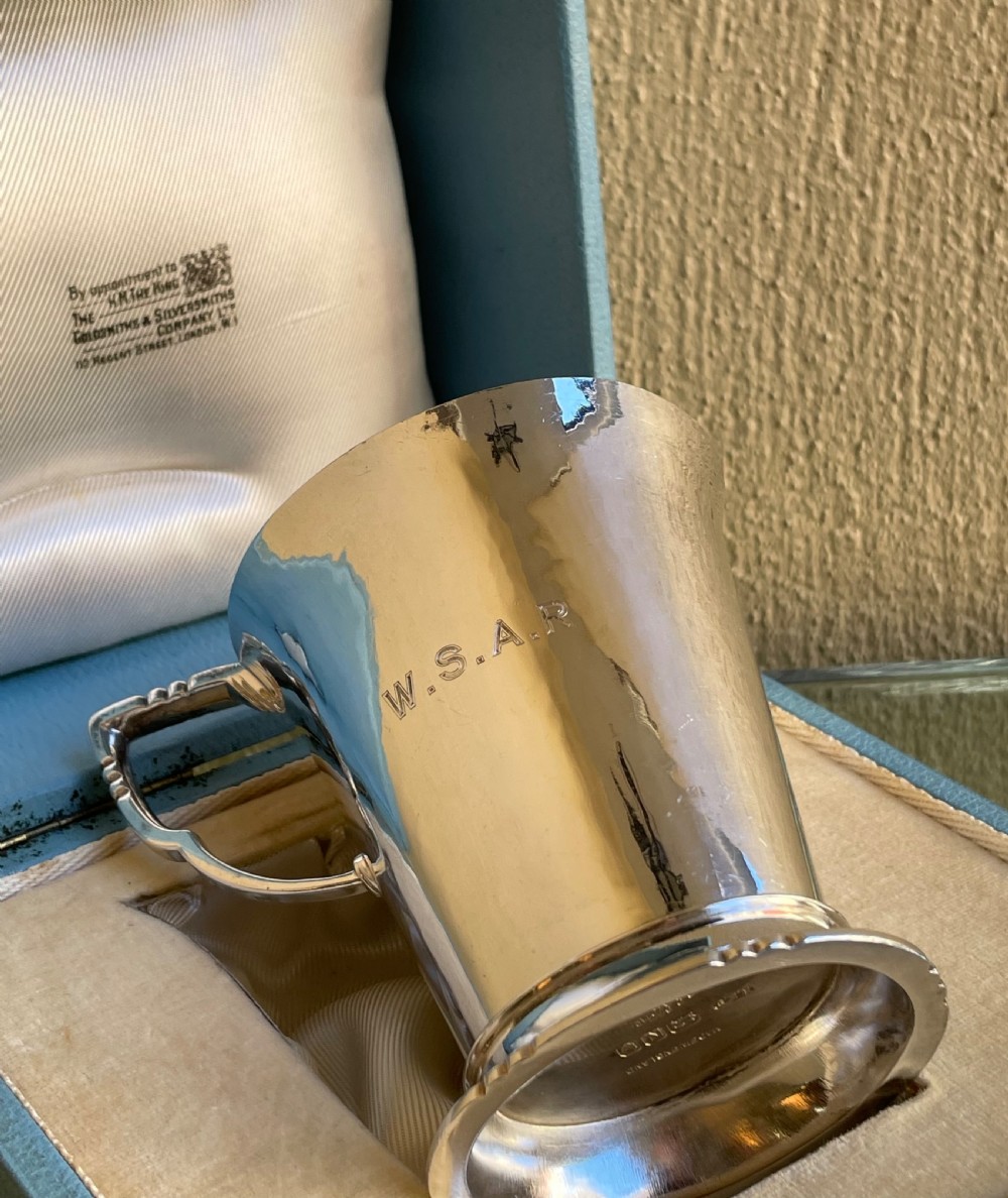 A tapered sterling silver christening mug with an engraved rabbit motif resting inside a light blue presentation case. View V