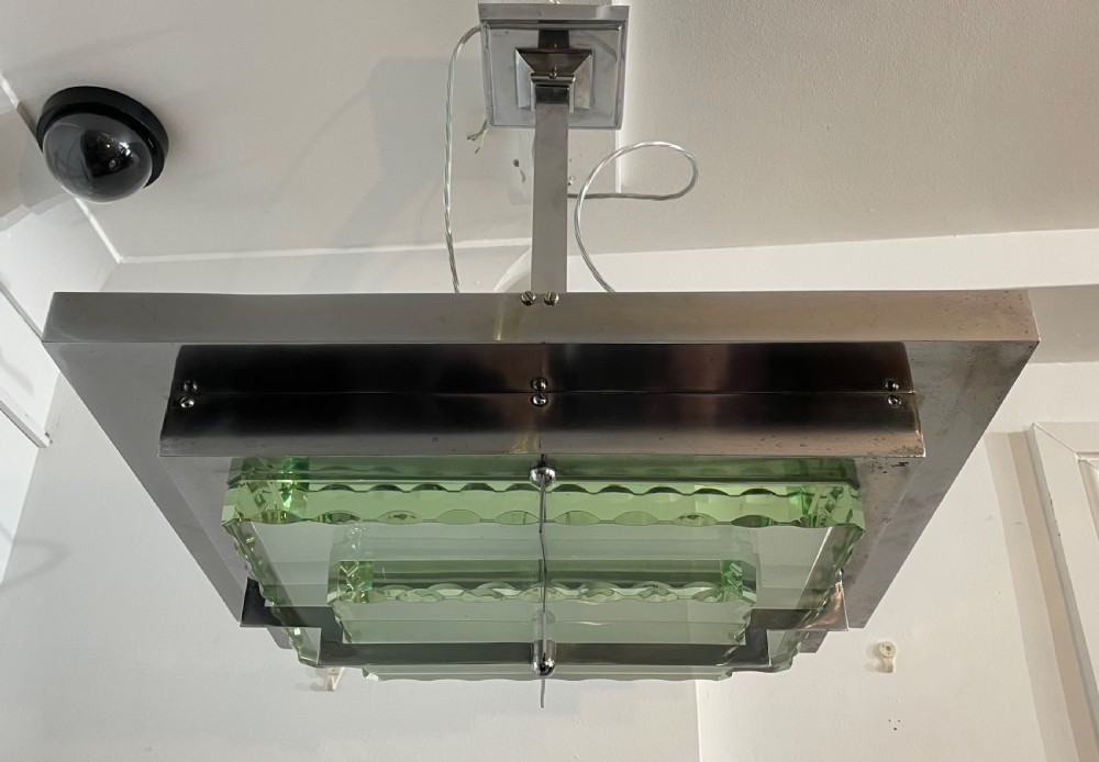 An Art Deco hanging pendant light featuring a tiered chrome-plated metal frame holding layered green glass plates suspended from a central stem. View II