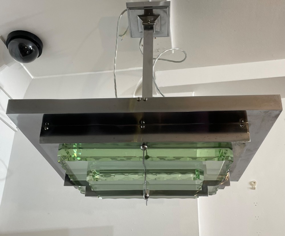 An Art Deco hanging pendant light featuring a tiered chrome-plated metal frame holding layered green glass plates suspended from a central stem. View V