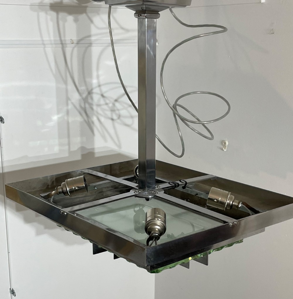An Art Deco hanging pendant light featuring a tiered chrome-plated metal frame holding layered green glass plates suspended from a central stem. View VI