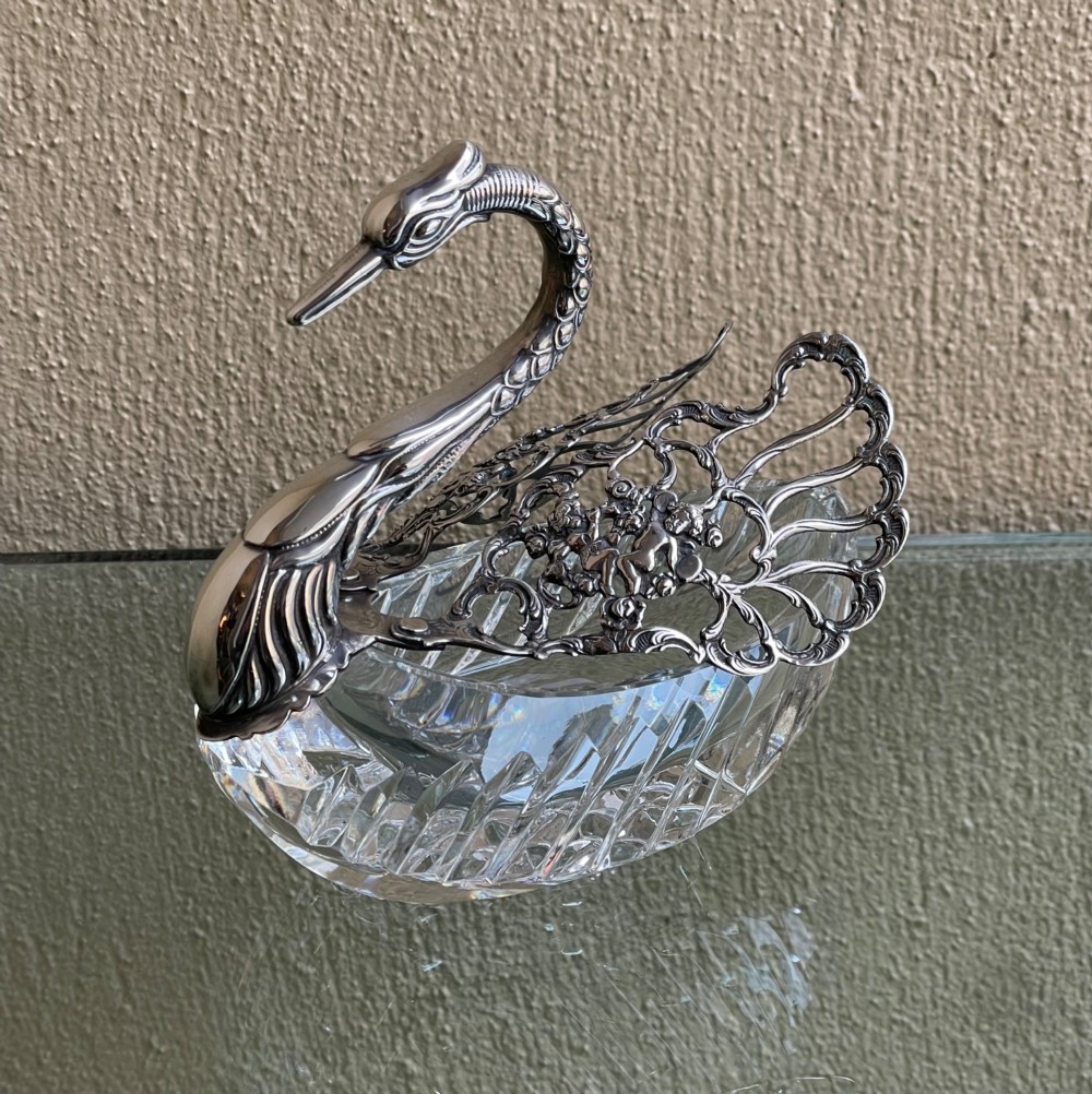 A cut glass dish featuring an ornate silver-plated swan head, neck, and articulated pierced wings.