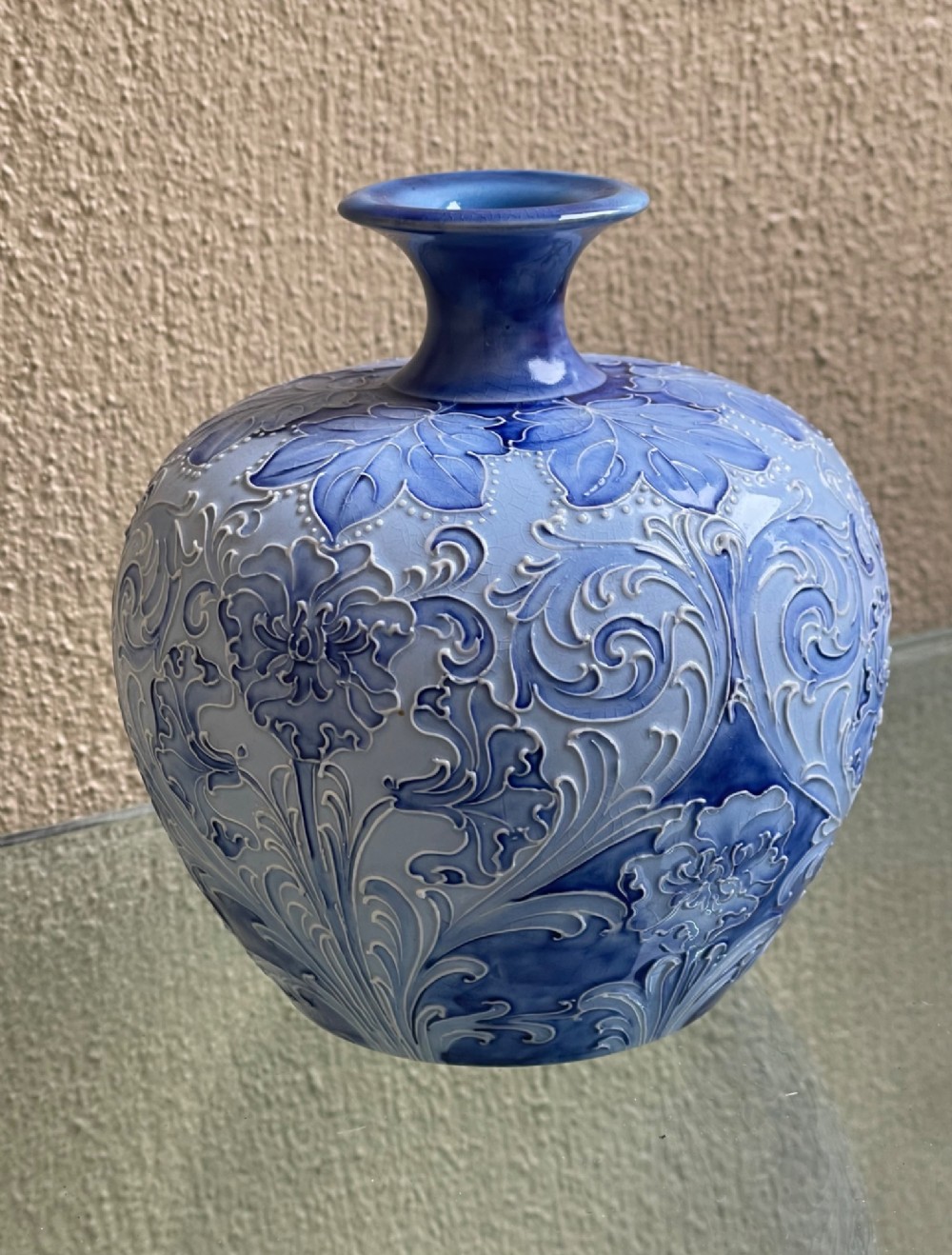 A bulbous blue ceramic vase with raised tubelined floral decoration and a short flared neck. View III