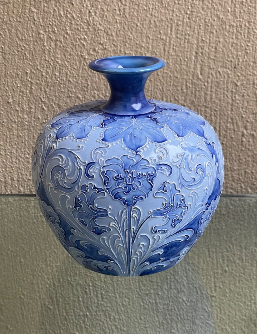 A bulbous blue ceramic vase with raised tubelined floral decoration and a short flared neck. View IV