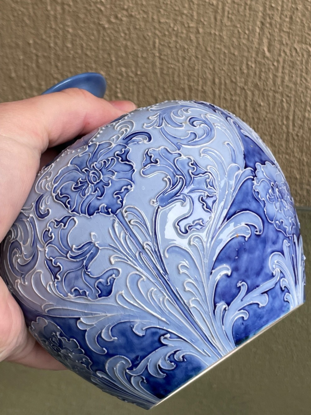 A bulbous blue ceramic vase with raised tubelined floral decoration and a short flared neck. View V