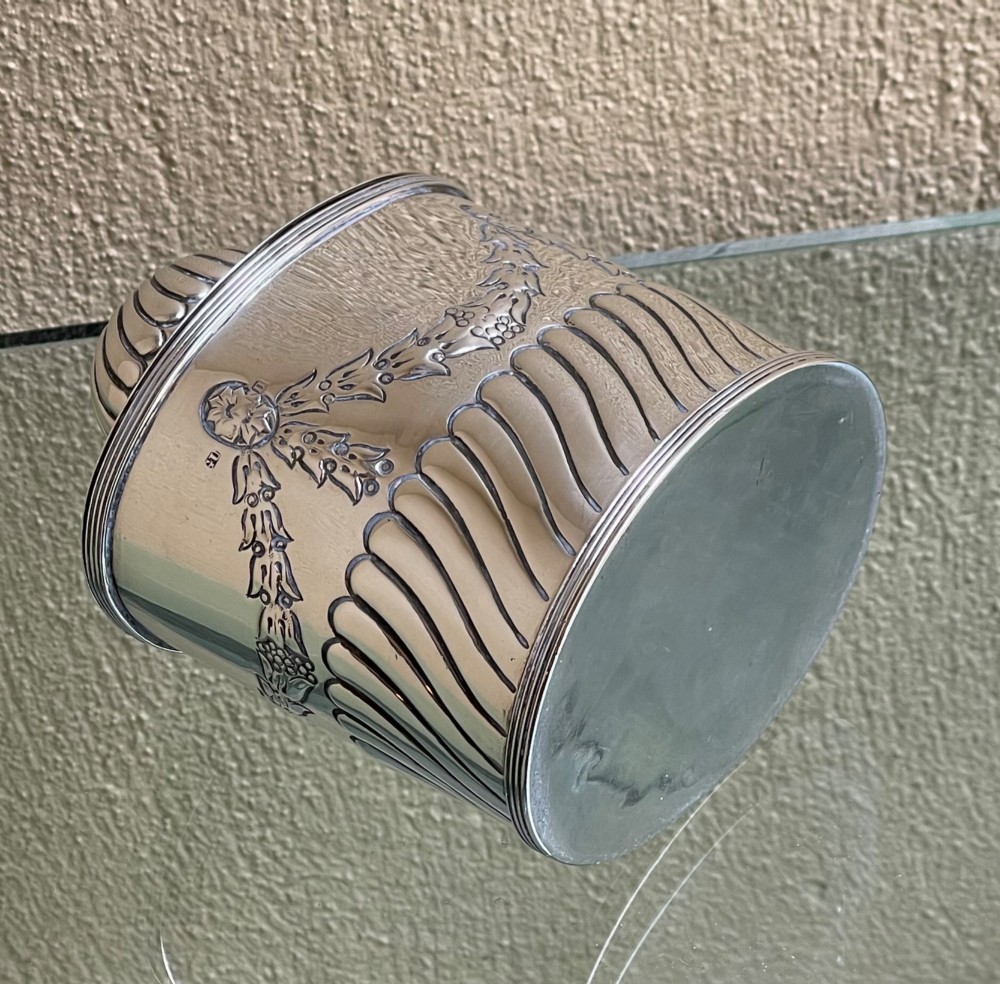A cylindrical Edwardian sterling silver tea caddy featuring embossed floral garlands and spiral fluting around the lower body. View IV