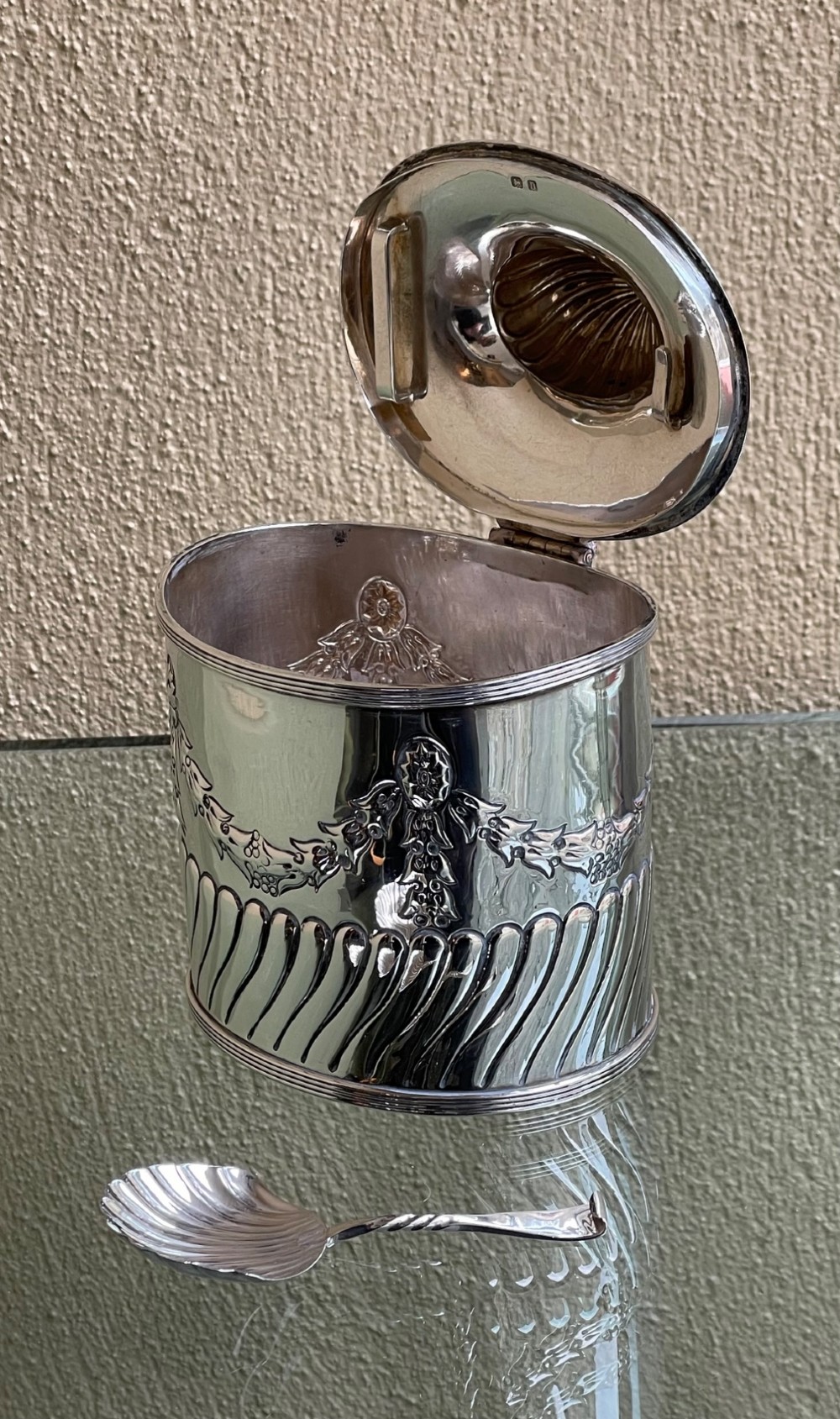 A cylindrical Edwardian sterling silver tea caddy featuring embossed floral garlands and spiral fluting around the lower body. View VII