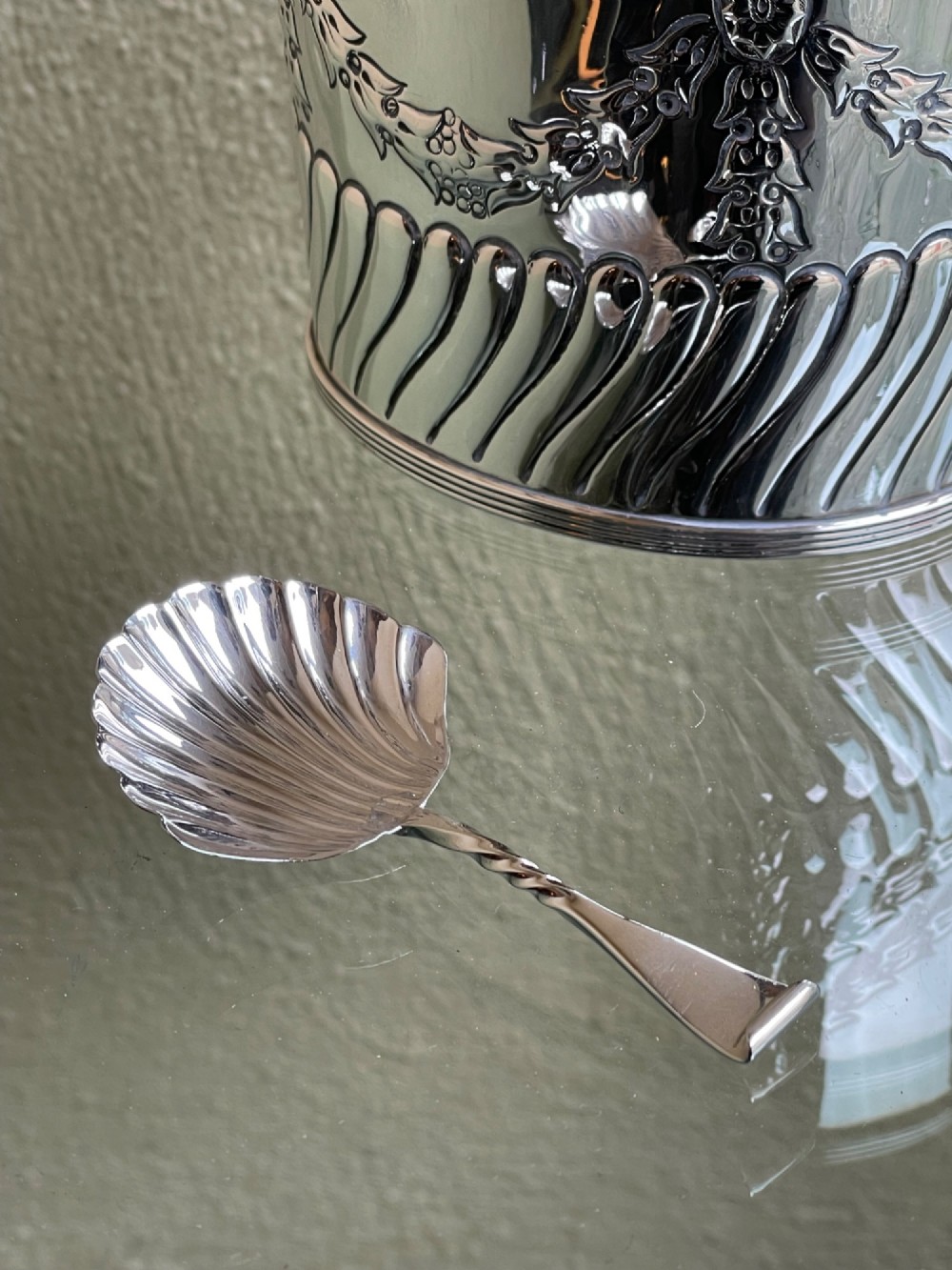 A cylindrical Edwardian sterling silver tea caddy featuring embossed floral garlands and spiral fluting around the lower body. View IX