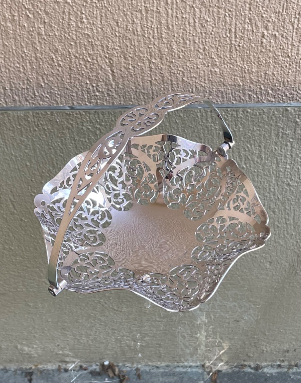 A pierced silver bonbon dish featuring a hinged overhead swing handle and intricate floral lattice openwork.