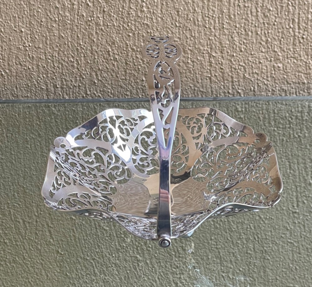 A pierced silver bonbon dish featuring a hinged overhead swing handle and intricate floral lattice openwork. View III