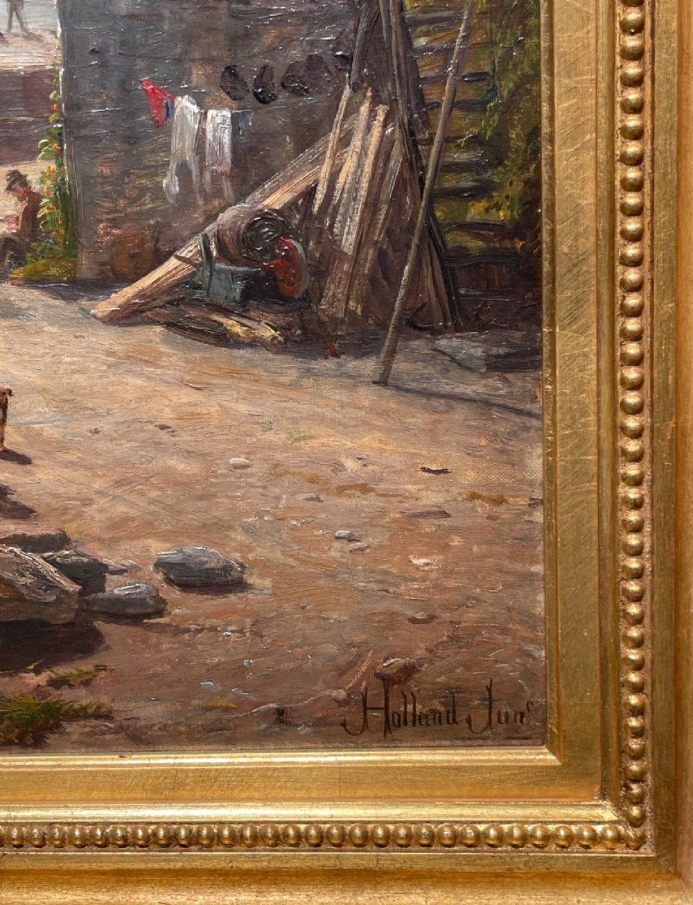 A framed 19th-century oil painting depicting a coastal village scene in Port Erin with stone cottages, figures, and fishing boats on the sea, enclosed within a gilded wooden frame. View III