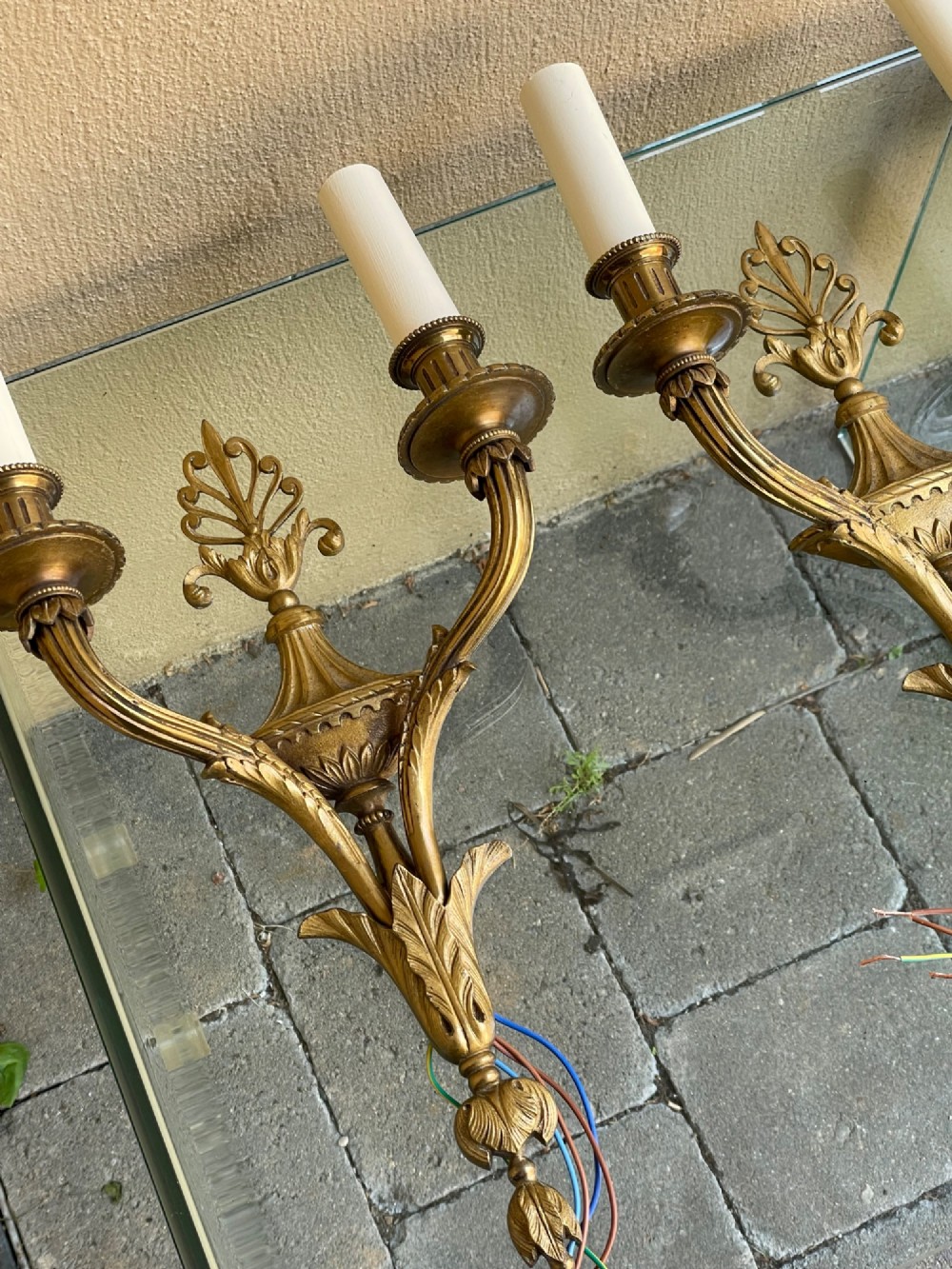 A pair of French Neoclassical gilded bronze wall sconces featuring urn-shaped central bodies, twin branches, acanthus leaf embellishments, and white candle sleeves. View II