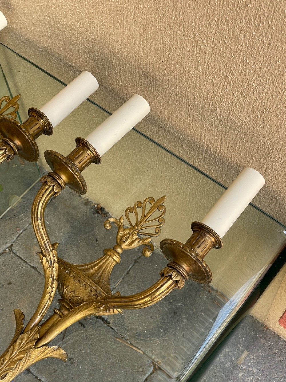 A pair of French Neoclassical gilded bronze wall sconces featuring urn-shaped central bodies, twin branches, acanthus leaf embellishments, and white candle sleeves. View III