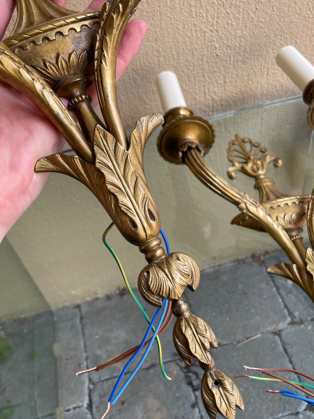 A pair of French Neoclassical gilded bronze wall sconces featuring urn-shaped central bodies, twin branches, acanthus leaf embellishments, and white candle sleeves. View IV