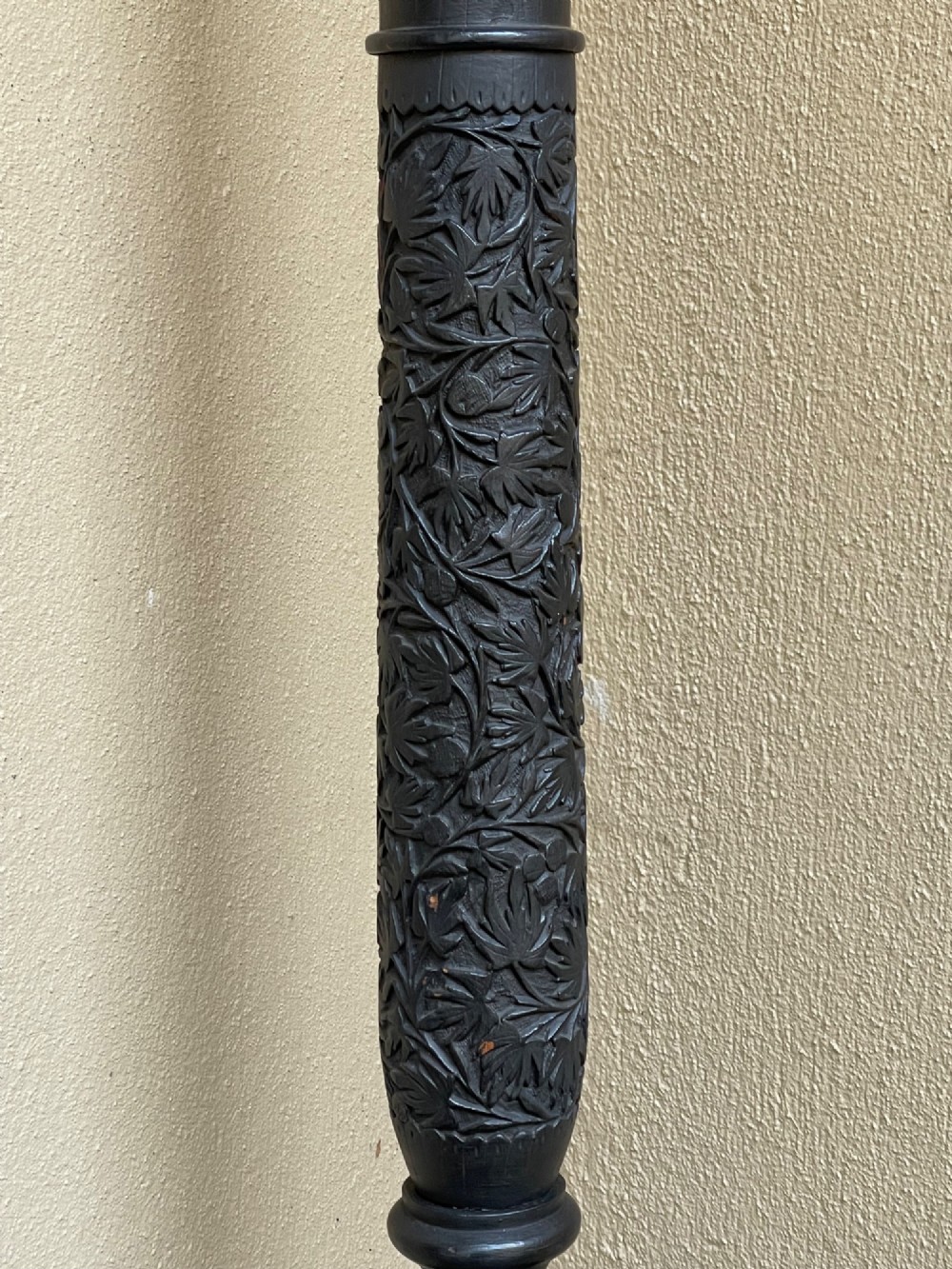 A tall Anglo-Indian hand-carved dark wood standard lamp featuring intricate foliate patterns on a turned column and circular base, topped with a brass bulb socket. View IV