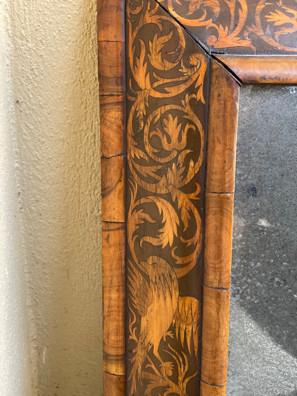 A rectangular antique William and Mary cushion-moulded wall mirror featuring intricate foliate marquetry inlay across the wooden frame and an aged glass pane. View IV