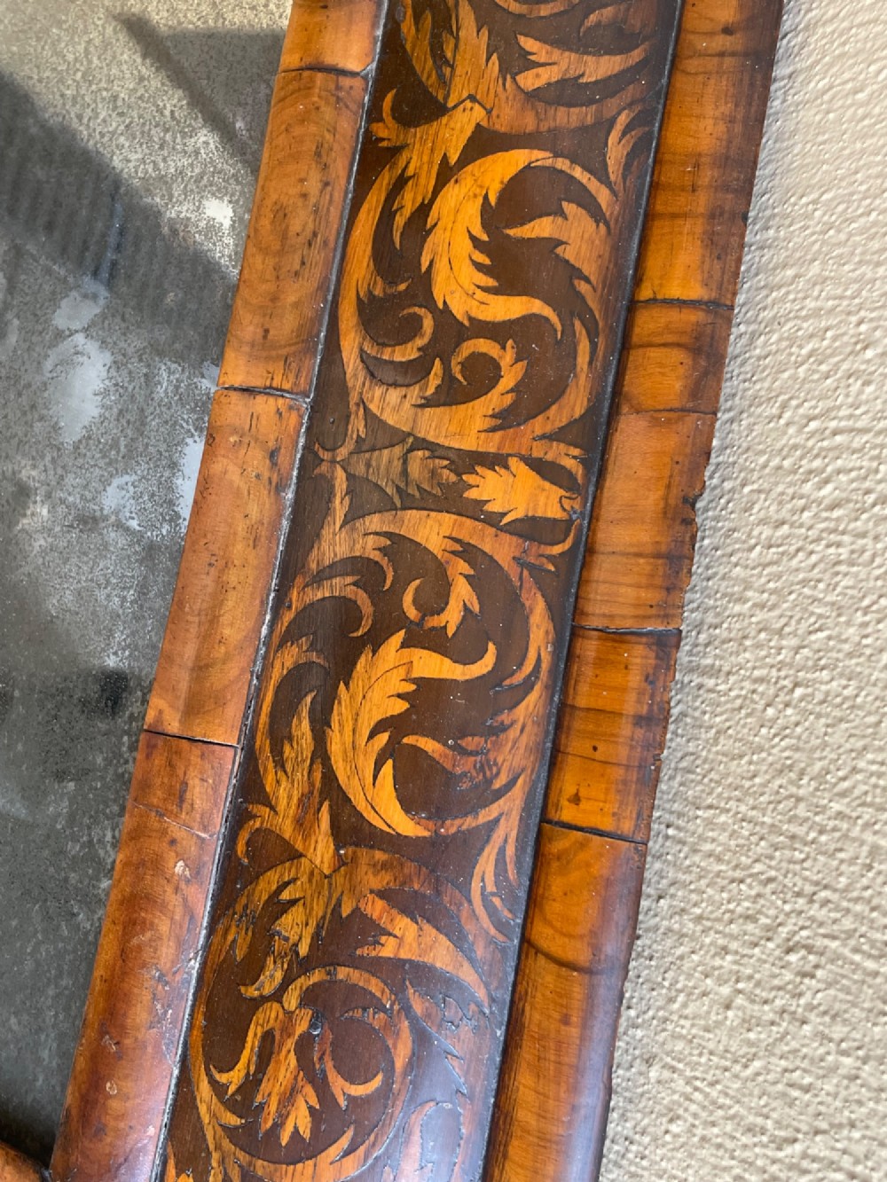 A rectangular antique William and Mary cushion-moulded wall mirror featuring intricate foliate marquetry inlay across the wooden frame and an aged glass pane. View V