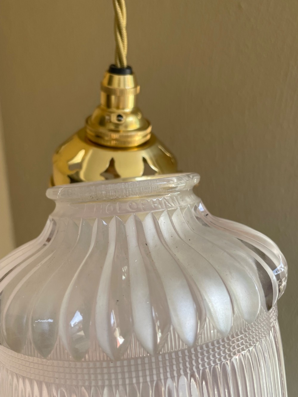 A clear ribbed Holophane glass pendant light featuring a brass gallery fitment and twisted fabric cord. View III