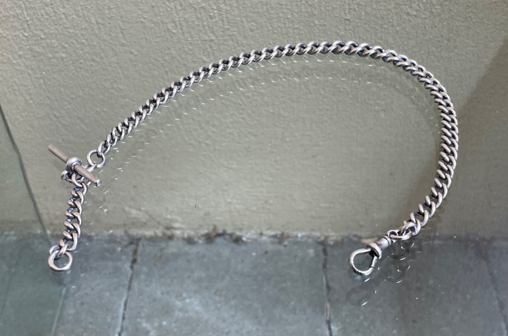 A late Victorian sterling silver single Albert chain featuring curb links, a T-bar, and a swivel clasp.