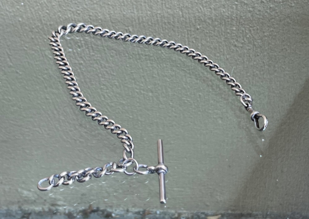 A late Victorian sterling silver single Albert chain featuring curb links, a T-bar, and a swivel clasp. View II