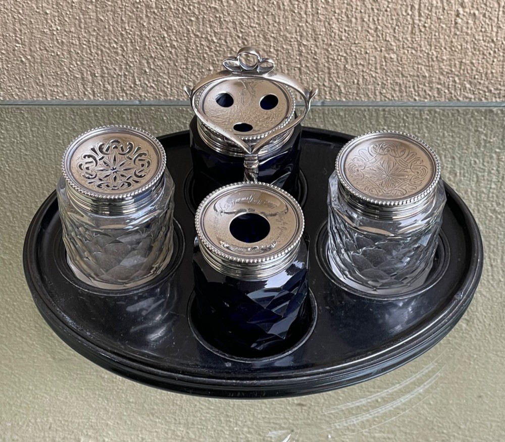 An oval ebony tray holding four diamond-cut glass pots with pierced sterling silver lids and a central silver loop handle. View II