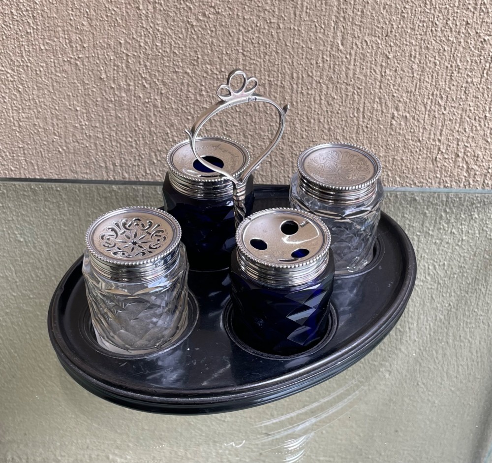 An oval ebony tray holding four diamond-cut glass pots with pierced sterling silver lids and a central silver loop handle. View IV
