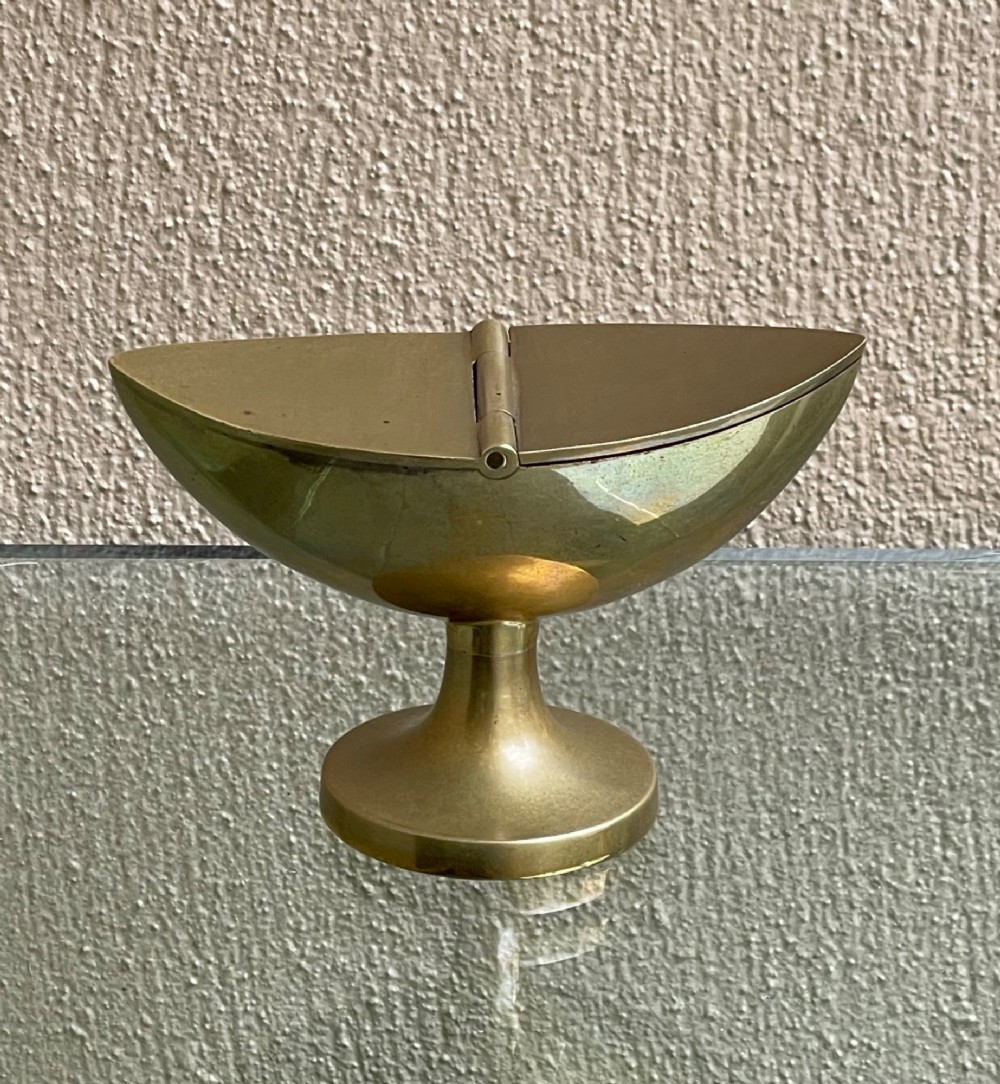A Georgian navette-shaped brass table snuff box with a central hinged lid elevated on a circular pedestal foot.