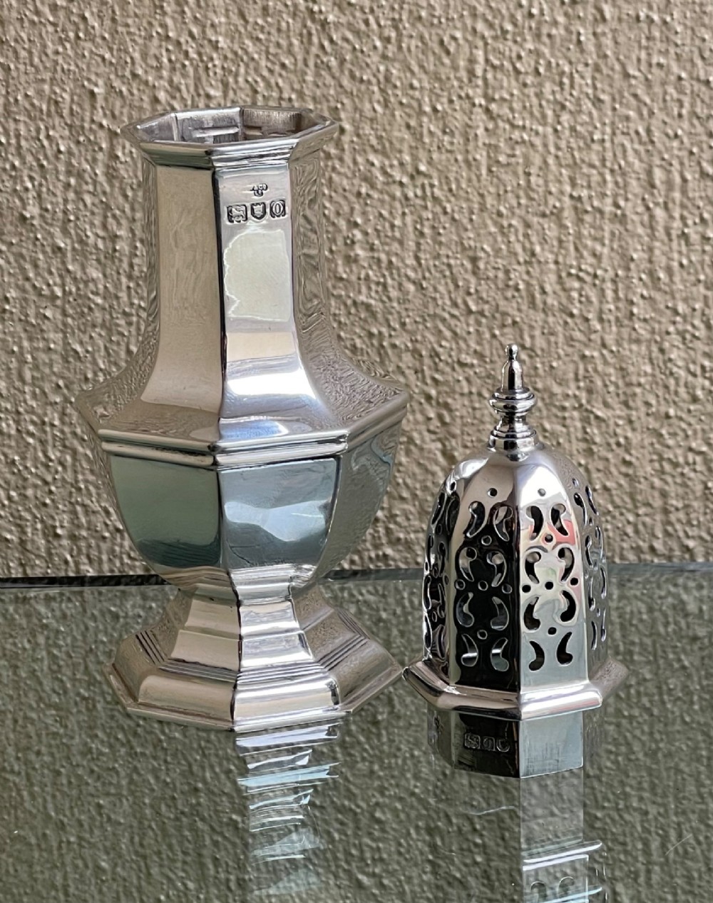 An Edwardian octagonal sterling silver sugar caster featuring a pierced domed lid topped with a finial and stamped with British hallmarks on the neck. View IV