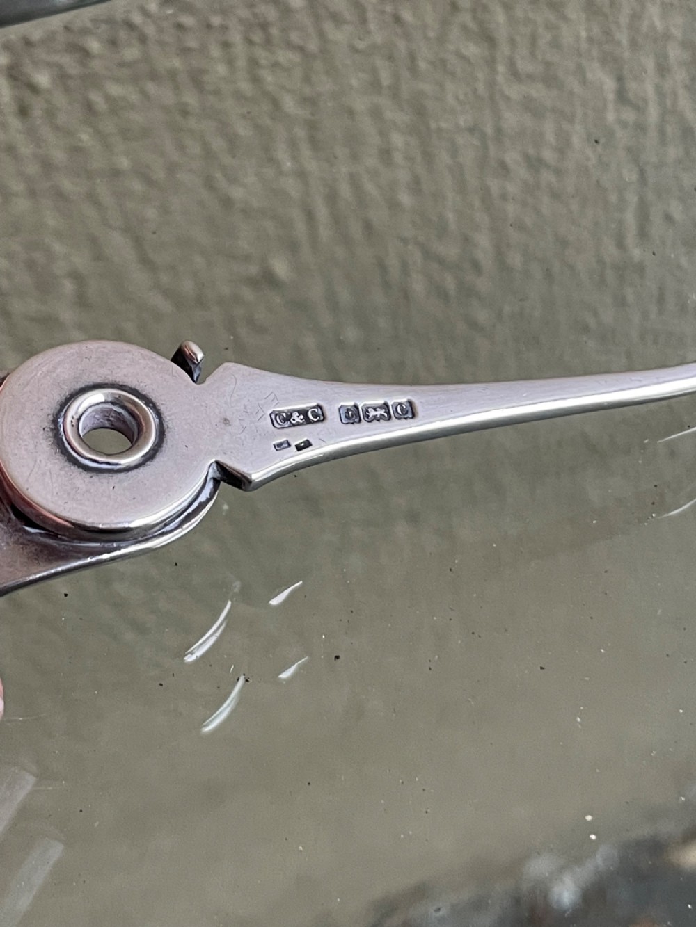 An antique sterling silver shoe horn featuring an integrated folding button hook attachment and visible British hallmarks. View IV