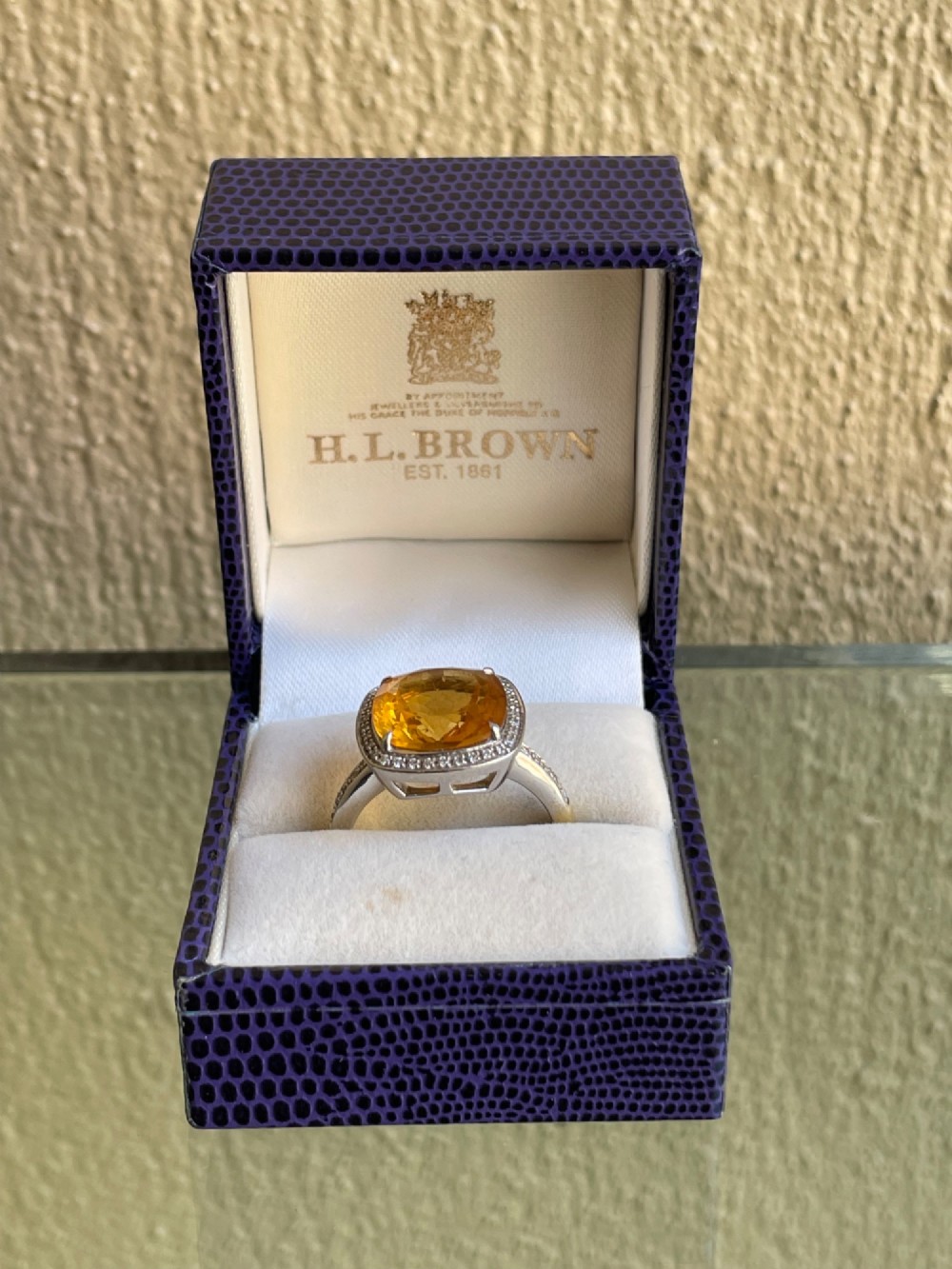A cushion-cut yellow citrine gemstone set in a white metal ring surrounded by a border of small brilliant-cut diamonds. View V