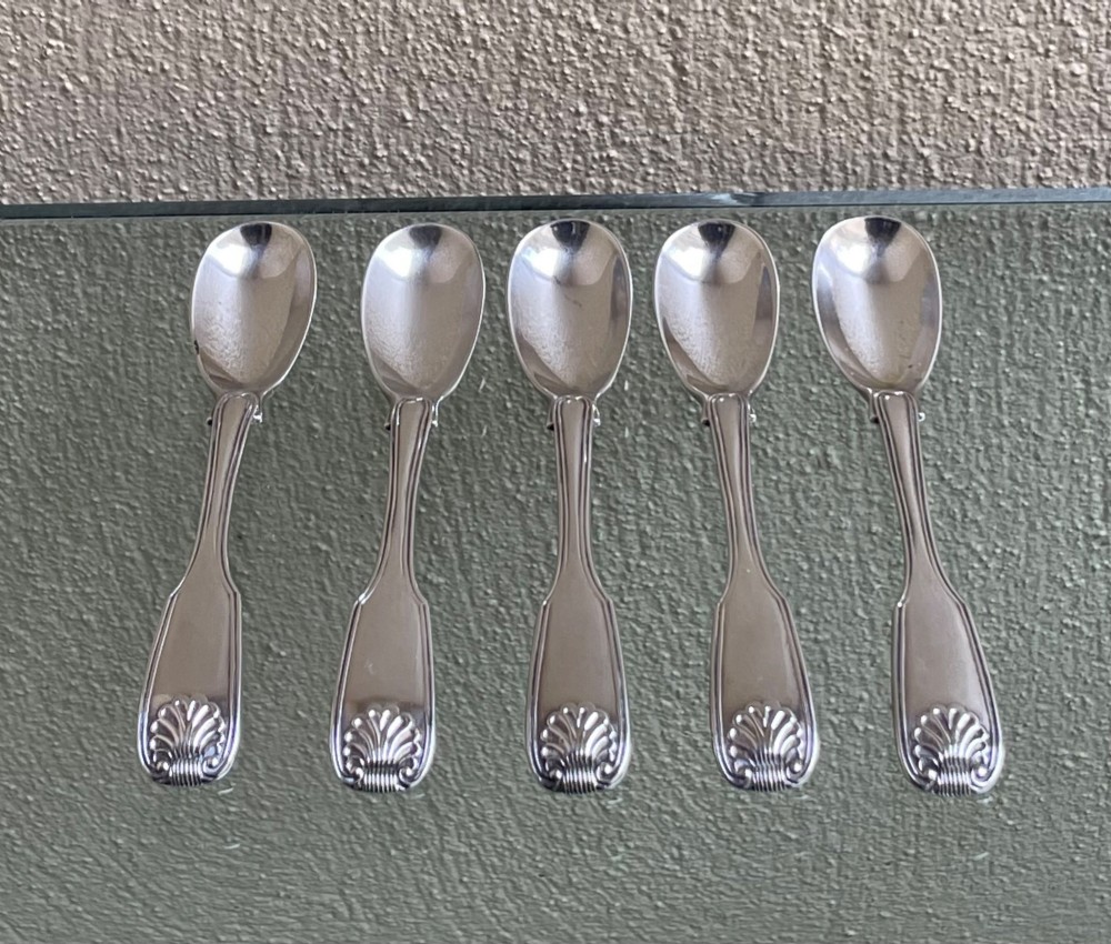 A set of five George IV sterling silver egg spoons featuring fiddle, thread, and shell pattern terminals displayed side by side.