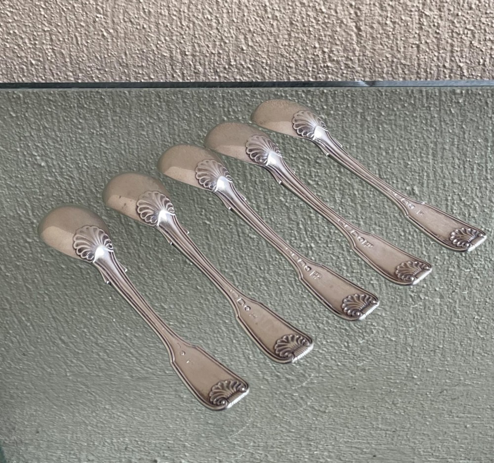 A set of five George IV sterling silver egg spoons featuring fiddle, thread, and shell pattern terminals displayed side by side. View IV