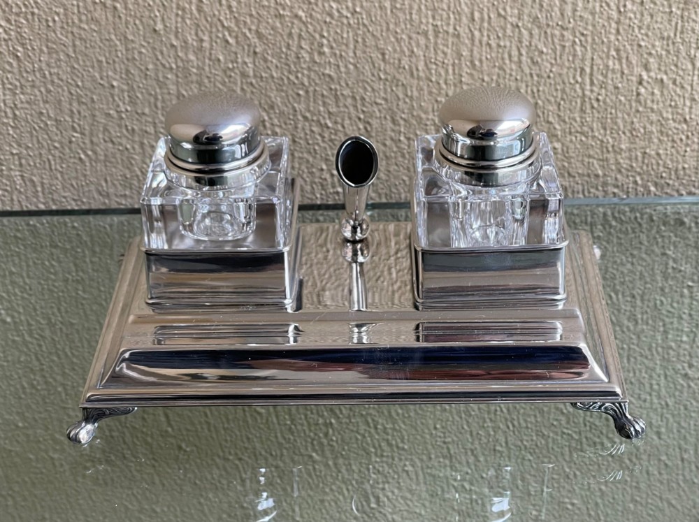 A hallmarked solid silver inkstand featuring two square cut-glass inkwells with silver lids mounted on a stepped tray with decorative feet. View II