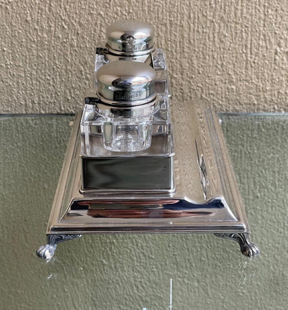 A hallmarked solid silver inkstand featuring two square cut-glass inkwells with silver lids mounted on a stepped tray with decorative feet. View III