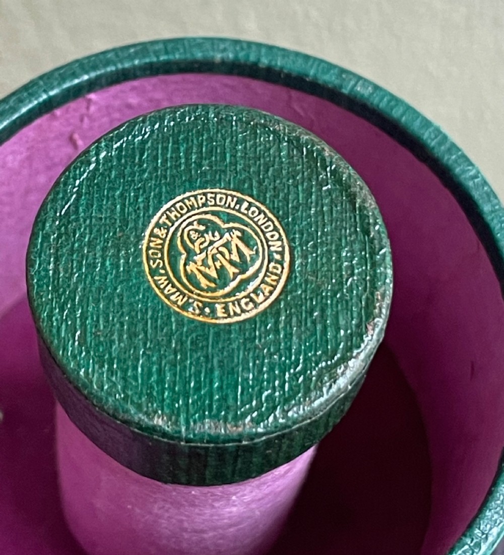 A 19th-century cylindrical burgundy textured leather case with gold embossed text reading Medicine Glass and Minim Measure alongside its fitted clear glass measuring cup. View V