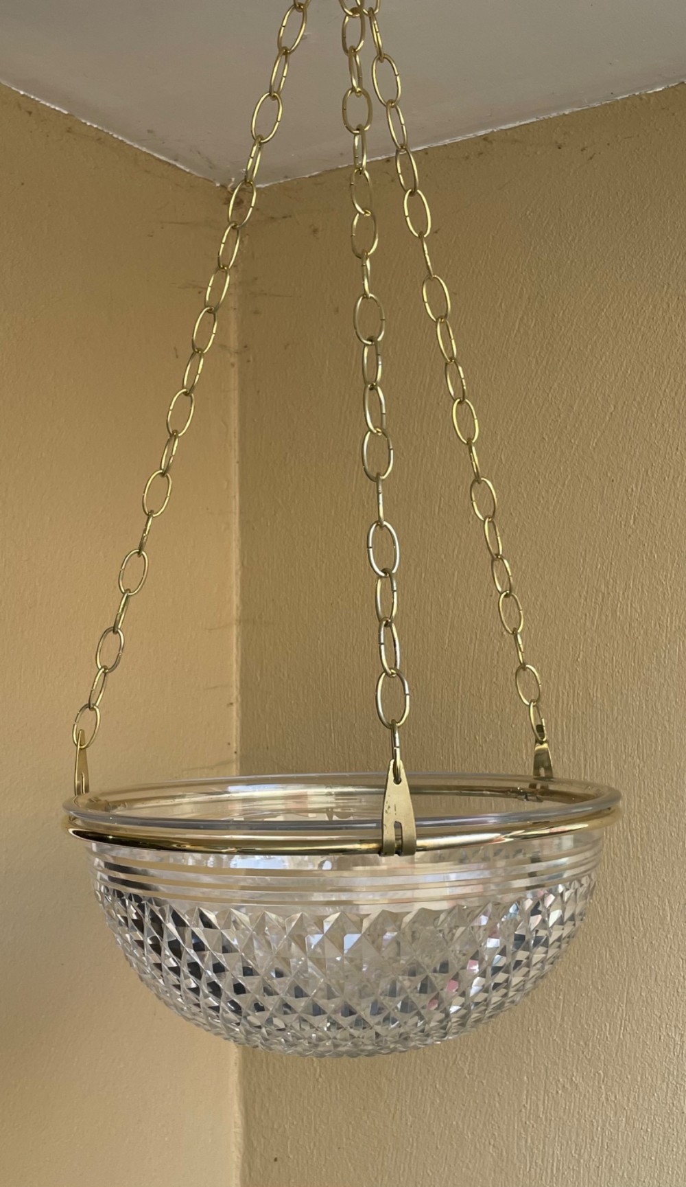 An Edwardian period cut glass bowl light shade suspended by three brass link chains connected to a central brass rim.