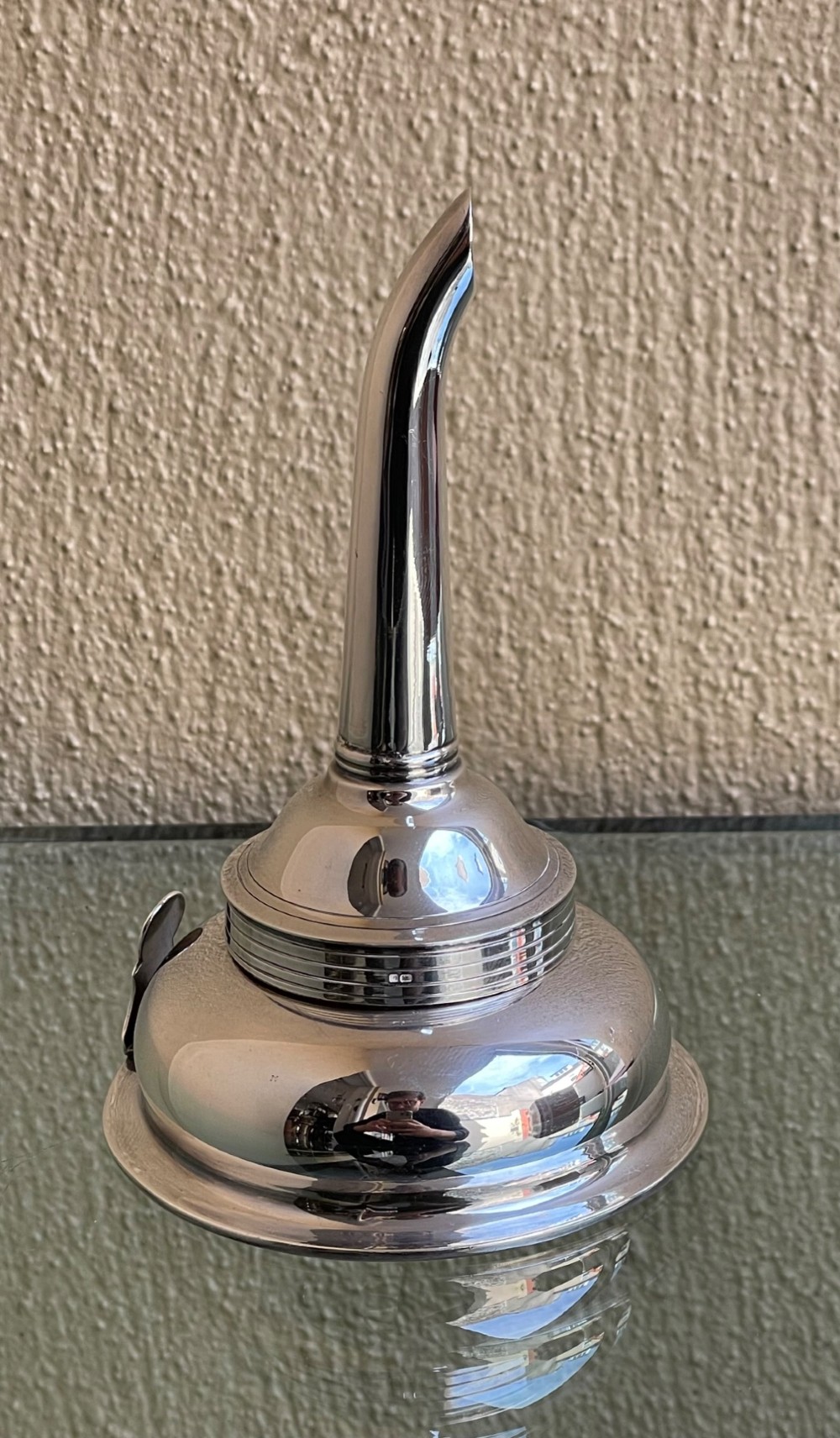 A polished sterling silver wine funnel featuring a wide rimmed bowl and a tapered curved spout resting on a flat surface. View II