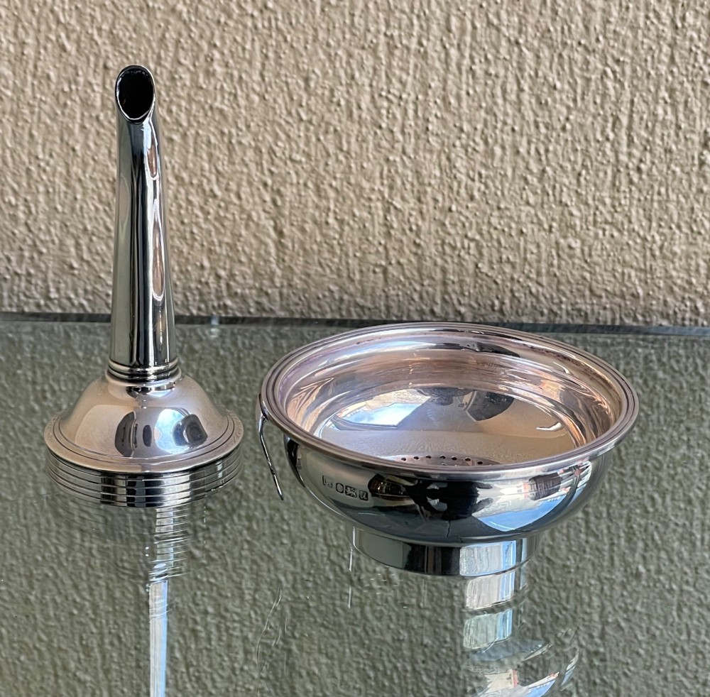 A polished sterling silver wine funnel featuring a wide rimmed bowl and a tapered curved spout resting on a flat surface. View III