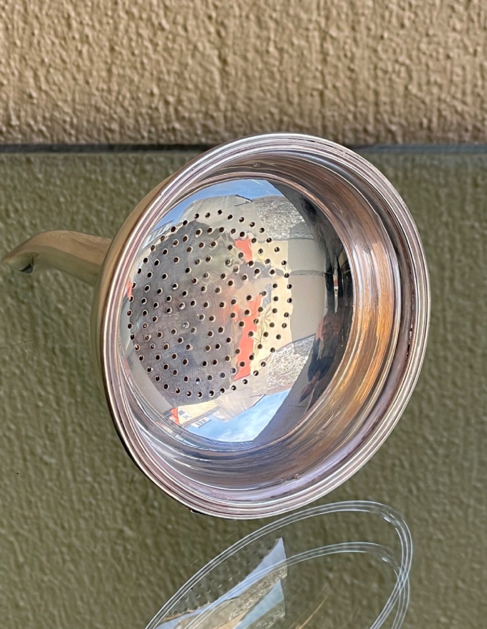 A polished sterling silver wine funnel featuring a wide rimmed bowl and a tapered curved spout resting on a flat surface. View IV