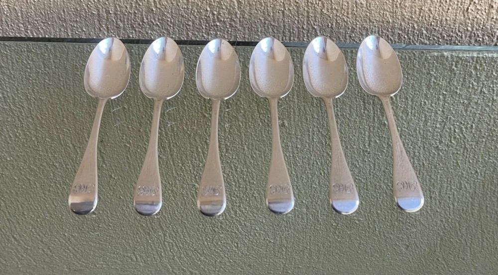 A set of six Victorian silver teaspoons featuring oval bowls and engraved initial monograms on the handles.