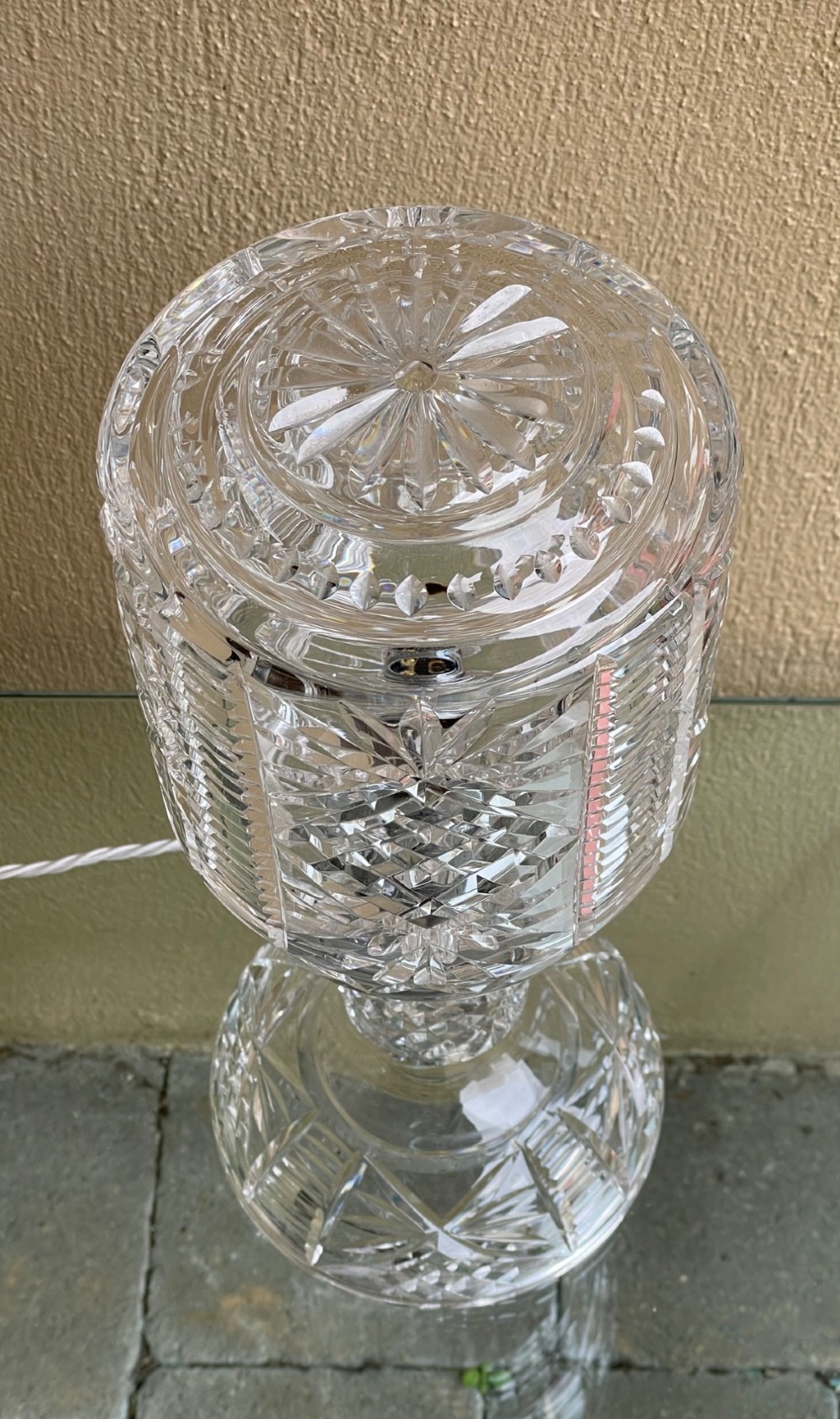 A clear cut glass table lamp featuring a cylindrical geometric shade set on a faceted glass pedestal stem and base. View II