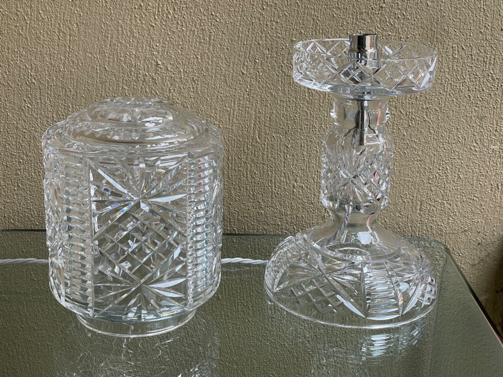 A clear cut glass table lamp featuring a cylindrical geometric shade set on a faceted glass pedestal stem and base. View IV