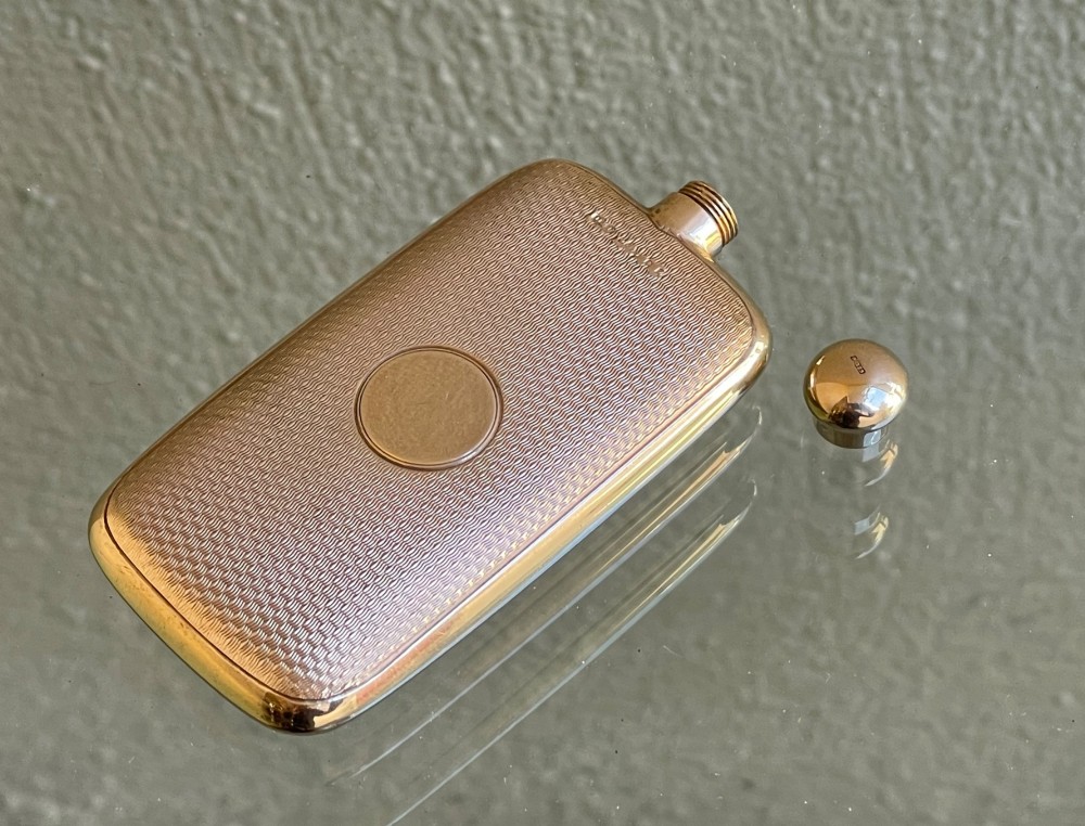 A small rectangular 9ct yellow gold scent flask featuring fine engine-turned geometric detailing, a central circular cartouche, and a screw top. View VI