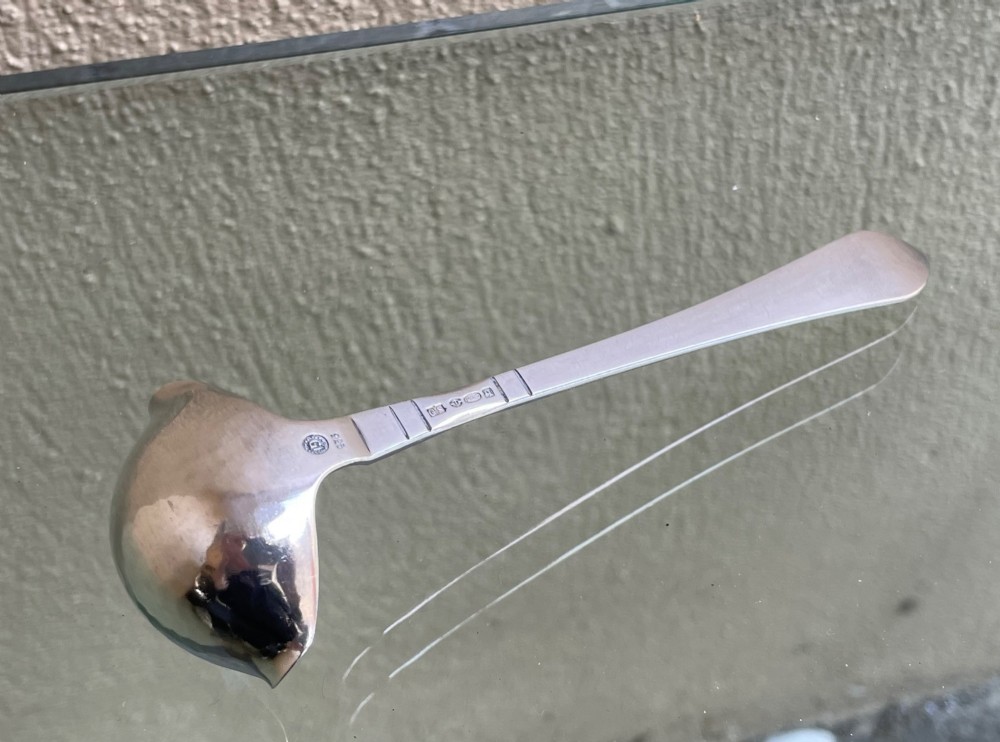 A sterling silver Georg Jensen sauce ladle with a side pouring spout and a slender handle with linear accents. View III