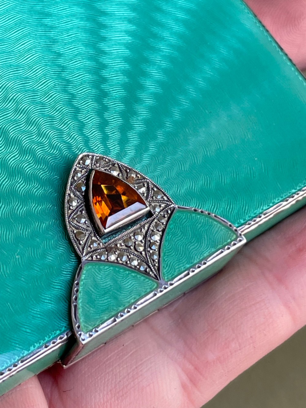 An Art Deco rectangular silver card case featuring turquoise sunburst guilloche enamel and a triangular gemstone clasp. View V