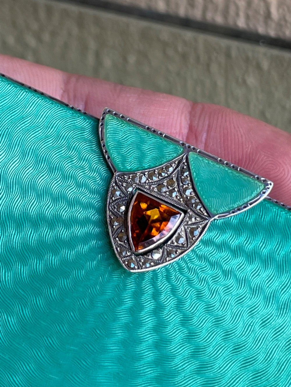 An Art Deco rectangular silver card case featuring turquoise sunburst guilloche enamel and a triangular gemstone clasp. View VI