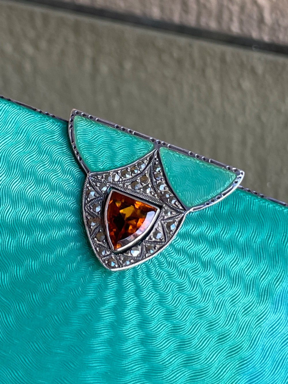 An Art Deco rectangular silver card case featuring turquoise sunburst guilloche enamel and a triangular gemstone clasp. View VII